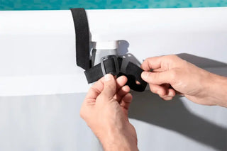Hand som justerar en svart rem med spänne för Hydro-PRO Swimulator städprodukter