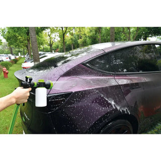 Handhållet skumkanon med behållare rengör en lila bil under vattning