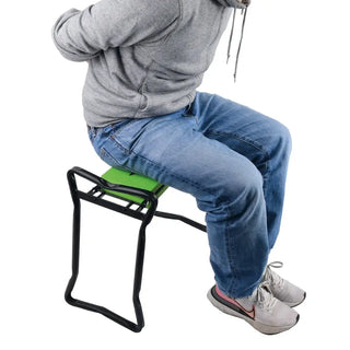 Person sittande på Yardsmith trädgårdspall med grönt och svart metallstöd