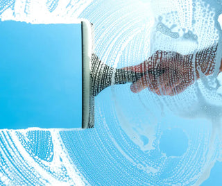 Rakel som rengör ett fönster med tvål.