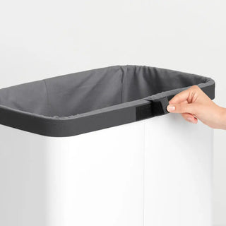 Vit tvättkorg med mörkgrå liner och lock, perfekt för städprodukter och rengöringsmedel