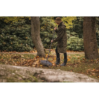 Person raking autumn leaves with Fiskars Solid™ M lövräfsa runt träd