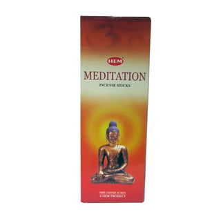 En ask med HEM Meditation-rökelsestickor med en Buddhastaty.