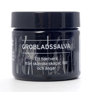 Svart burk med hudvårdsbalsam med växtillustrationer.