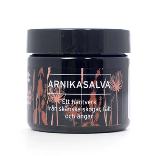 Mörkbrun burk med arnikasalva med botanisk illustration.