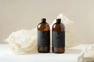 Två bärnstensfärgade flaskor med flytande handtvål med ekologiska eteriska oljor