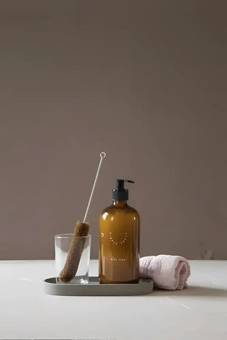 Amber glasflaska med svart pump från Simple Goods för städprodukter och rengöringsmedel