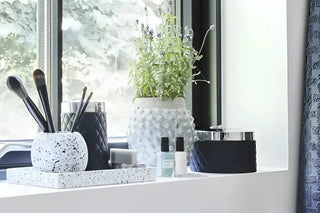 Decorativ vit terrazzbricka med matchande rund behållare och makeupborstar från Portia-serien