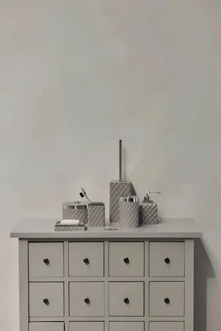 Sofistikerade portia-serien badrumsstädprodukter i grå texturerad design med silverdetaljer