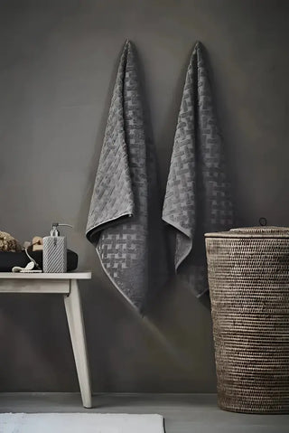 Två gråa, texturerade badhanddukar hänger på vägg, perfekt för flytande tvål och städprodukter