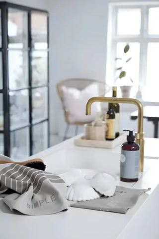 Guld kökskran med kvadratiskt nacke, passar perfekt med nordiska hem diskhandduk